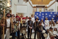 Grupa dzieci - aktorów, pasterzy i aniołów. W tle dorośli uczestnicy Jasełek.