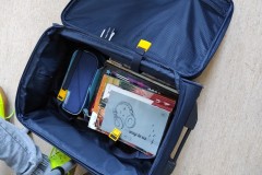 Otwarta walizka z przyborami szkolnymi- Dzień bez plecaka