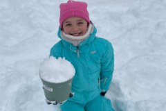 Uczennica siedząca na  śniegu, przygotowująca "śnieżne babki"