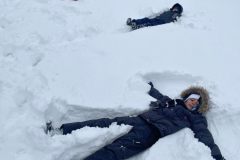 Uczniowie leżący na śniegu, wykonujący śnieżnego anioła