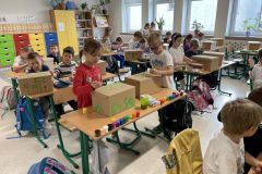 Uczniowie kl. 1b podczas malowania kartonowych pudełek w sali szkolnej.