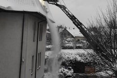Strażacy sciągający śnieg z dachu szkoły z wysięgnika strażackiego (2)
