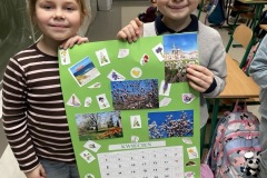 Uczniowie stojąc w klasie prezentują swoja pracę, kartę z kalendarza.