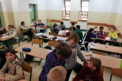 Widok sali lekcyjnej, uczniowie siedzą w zespołach po kilka osób i planują swoje działania.