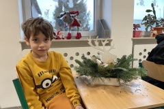 Chłopiec prezentuje swoja prace stroik świąteczny
