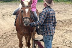 Uczennica siedząca na koniu przy wparciu opiekuna zwierzęcia