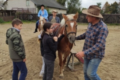 Uczniowie zebrani wokół konia rozmawiają z opiekunem
