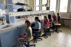 Grupa uczniów siedząca przy stole laboratoryjnym